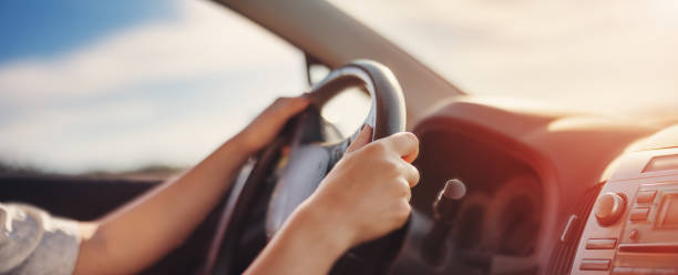 istock Woman's hands holding steering wheel inside car 1417637758