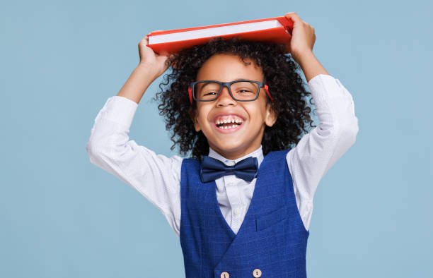 istock Happy ethnic schoolboy playing with book 1417642484