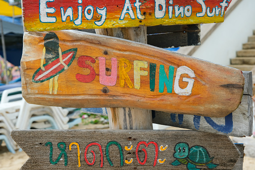 Creative travel or blog idea photo of signboard about surfing and reads on it “Kata beach” inThai Language in Kata Beach,Thailand