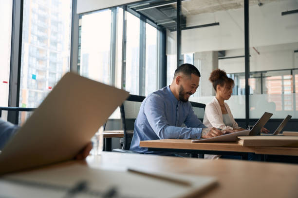 istock Photo of employees working in open office sit at laptops 1417648733