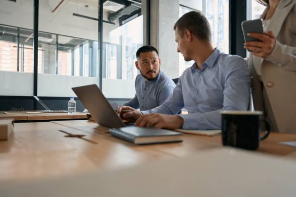 istock Colleagues men talking while sitting at table with laptop 1417649051