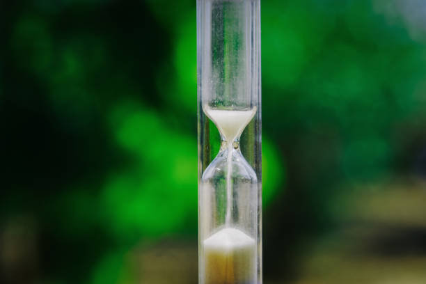 istock Hourglass with time passing falling sand against green bokeh. 1417650407