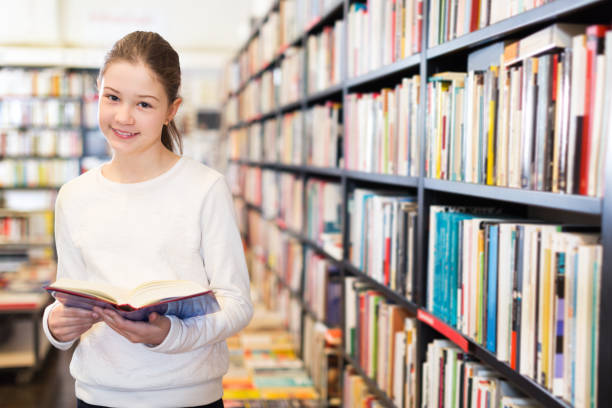 istock tweenager girl reading interesting book in bookstore 1417650456