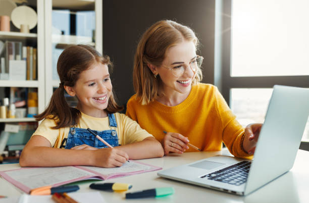 istock Cheerful mother doing homework with daughter at home 1417651007