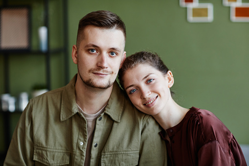 Portrait of young lovely couple smiling at camera sitting at home