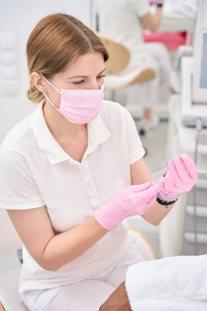 istock Cosmetician with disposable syringe in her hands sitting beside customer 1417660349
