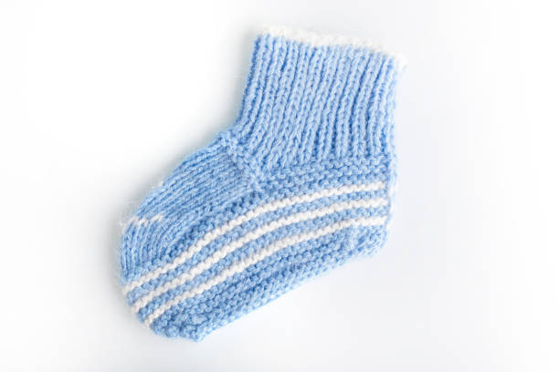 Knitted baby socks in blue color on a white background. The concept of warm things from a woolen thread