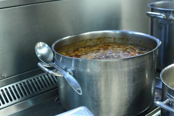 cooking concept - saucepan of boiling soup on oven in a restaurant kitchen
