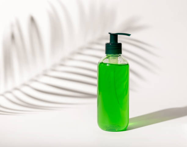 istock Cosmetic pump dispenser bottle filled with green liquid on white, Palm leaf hard shadows 1417664319
