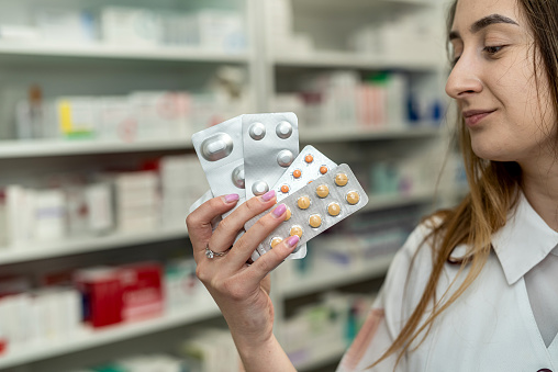 female pharmacist with a cardboard package of medicines in her hands at work. Healthcare concept