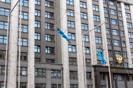 Moscow, Russia, June 16, 2019: a pair of aerial gymnasts perform tricks on a trapeze in front of the State Duma of Russia in Moscow.
