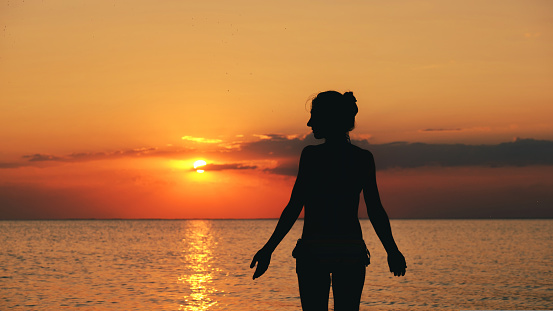 silhouette of woman on the beach at sunset. Young woman relaxing in summer sunset sky outdoor. People freedom style. download photo