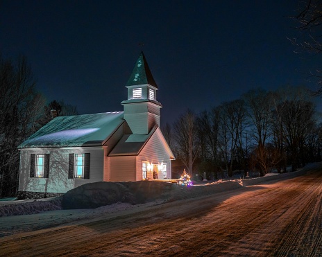 A long-exposure shot of a small white church surrounded by trees