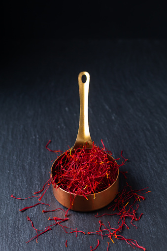 Food ingredient spice concept Saffron crocus spice in copper cup on black background with copy space