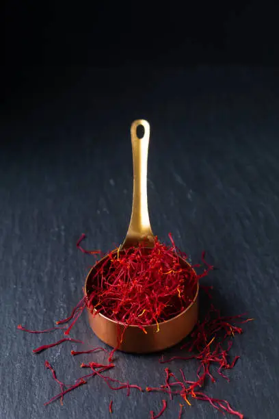 Food ingredient spice concept Saffron crocus spice in copper cup on black background with copy space