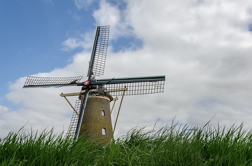A windmill in a grass field with a beautiful sky in the background