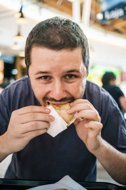 istock Man eating a steak on bread in a mall restaurant 1417679268