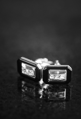 A grayscale shot of french cufflinks with diamonds