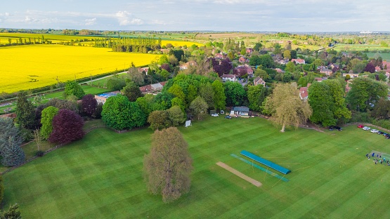 An English cricket pitch with colorful trees in a village in the English countryside