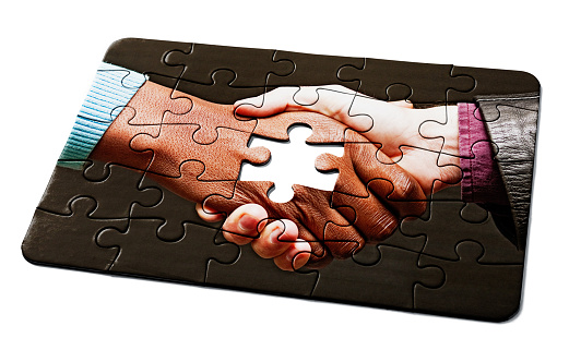 Hands trying to fit two puzzle pieces together.