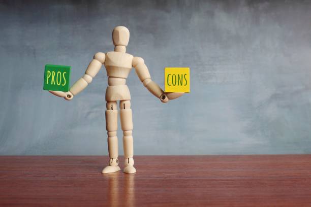 Pros and Cons balance concept. Wooden human figure balancing wooden cubes with text PROS and CONS. stock photo