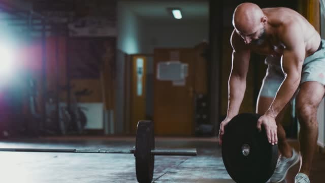 Bodybuilder prepares additional weights for a Barbell during training in the gym