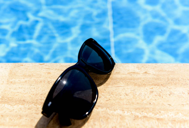 sunglasses standing by the pool in sunny weather