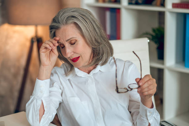 istock Mid aged businesswoman in white blouse looking tired after work 1417696057