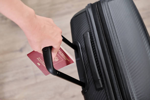 Hand with a Russian passport and a suitcase, emigration from the country, photo for an article or news, selective focus, blurred background stock photo