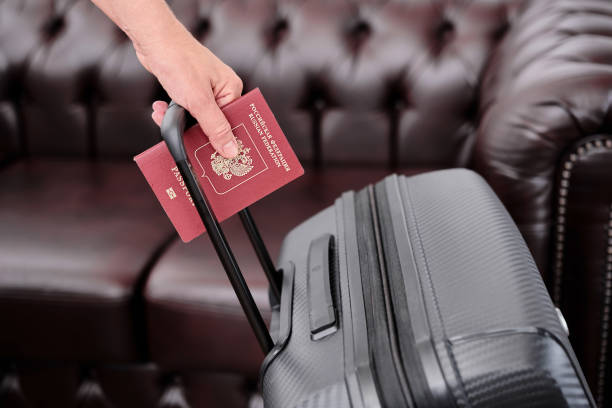 Selective focus, a woman's hand holds a Russian passport against the background of a black suitcase, a blurred background, emigration from the country, a photo for an article or news stock photo