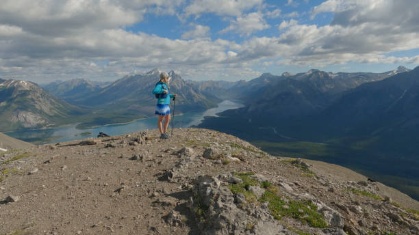 woman trail runner pauses on mountain ridge - conquering adversity wilderness area aspirations achievement imagens e fotografias de stock