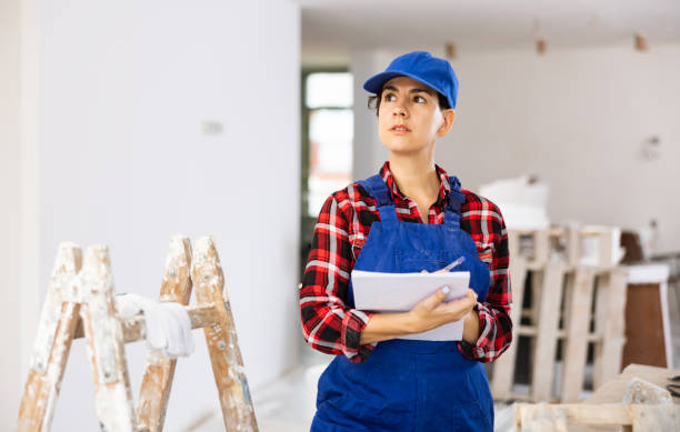 istock Focused young woman in blue overalls making checklist while planning building overhaul 1417704183