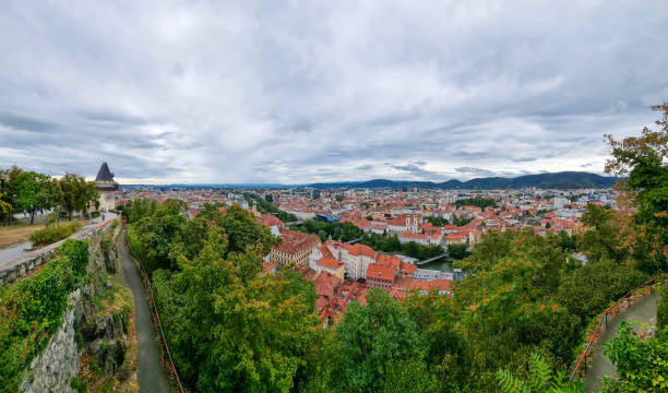 cityscape of old town of graz and the clock tower, famous tourist attraction in graz, steiermark, austria, in cloudy summer day. - graz austria clock tower styria imagens e fotografias de stock
