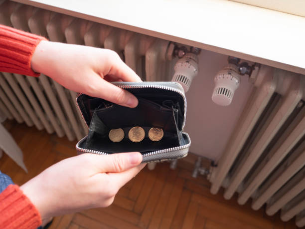 Heating bill. Increase in the cost of gas bill. Soaring energy prices. Increase in the price of natural gas. Energy crisis in Europe. Hands hold wallet with money near the radiator. Pay the bills. stock photo