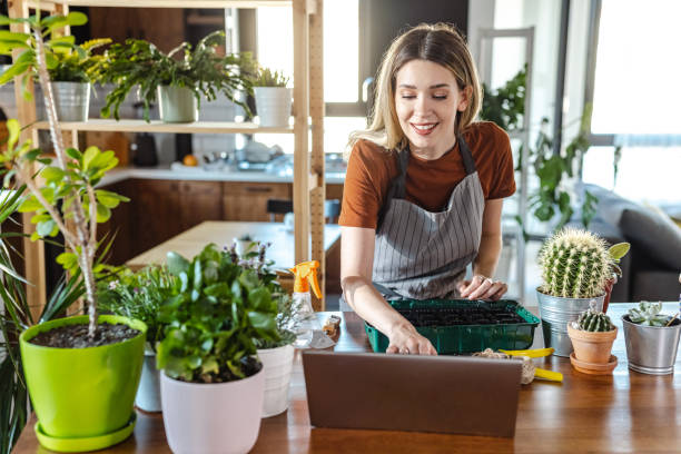 istock Beautiful woman replanting flower using online video instructions 1417705707