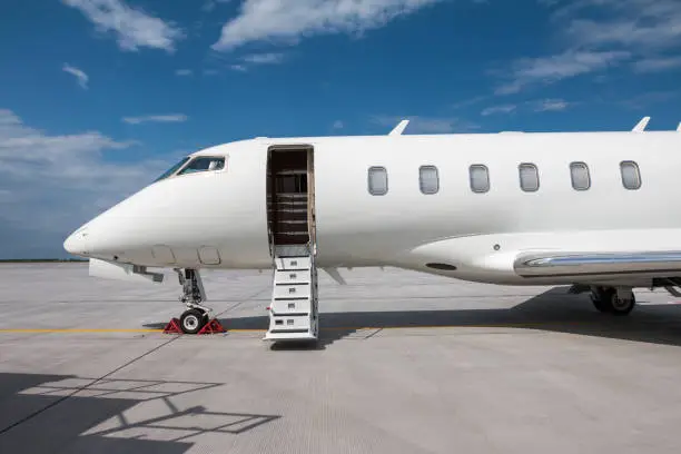 Close-up of the front of the modern white private jet with an opened gangway door