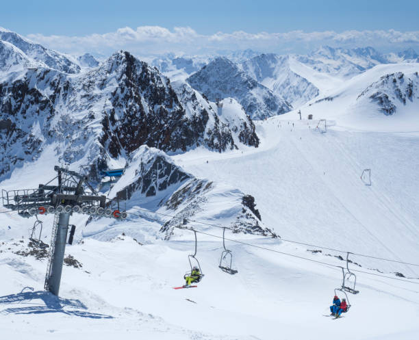 Scenic view from top of Wildspitze on winter landscape with snow covered mountain slopes and pistes and skiers on chair lift at Stubai Gletscher ski resort at spring sunny day. Blue sky background. Stubaital, Tyrol, Austrian Alps vista panorámica desde la cima de wildspitz en un paisaje invernal con laderas de montaña cubiertas de nieve y pistas y esquiadores en telesilla en la estación de esquí de stubai gletscher en el día soleado de primavera. fondo de cielo azul. stubaital