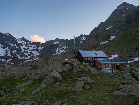 Evening sunset summer view of Bremer Hutte, an alpine mountian wooden hut with snow-capped moutain peaks, Stubai Alps, Tyrol, Austria.