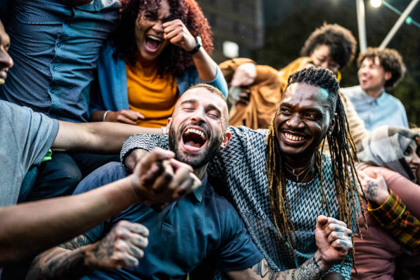 Friends watching a sports game and celebrating outdoors Friends watching a sports game and celebrating outdoors supporter stock pictures, royalty-free photos & images