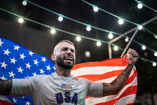 Mid adult man celebrating holding a american flag outdoors