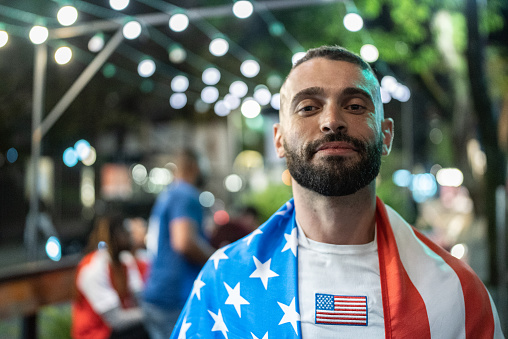 Portrait of a mid adult man with a american flag outdoors