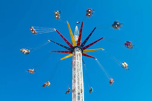 Hoorn, Netherlands, August 10, 2022; Children enjoy the high-speed merry-go-round at the funfair high in the blue sky.