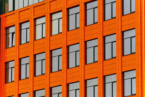 The facade of the new building is orange with dark-coloured windows