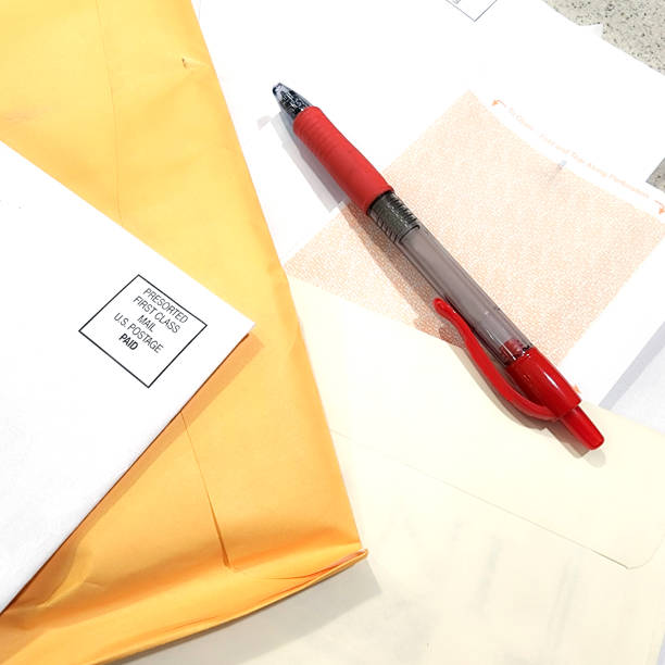 LV Finances - table scattered with mail that includes bills, personal correspondence and junk mail.  Red ball point pen.