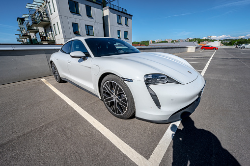 Mölndal, Sweden - June 04 2022: White 2022 Porsche Taycan electric sports car on a rooftop parking.