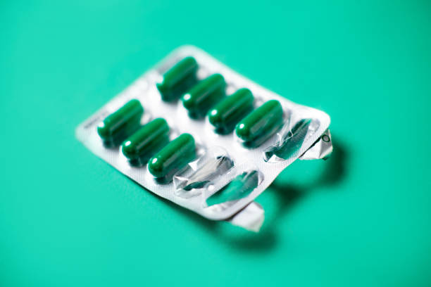 istock Started packing of tablets with green capsules. Green background. Probiotics, vitamins concept. 1417741726