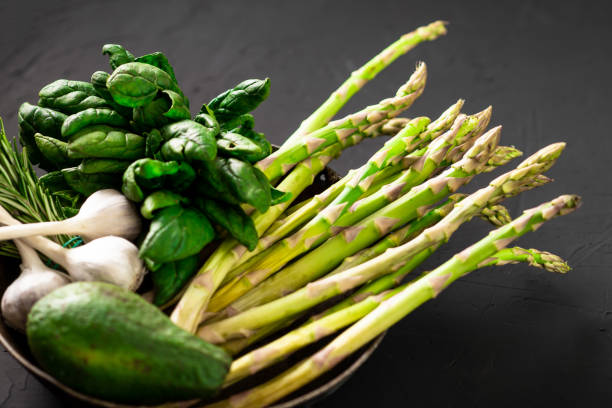 istock Various green vegetables on a dark background. Asparagus, spinach, avocado, garlic. Vegetarian food concept. 1417741774