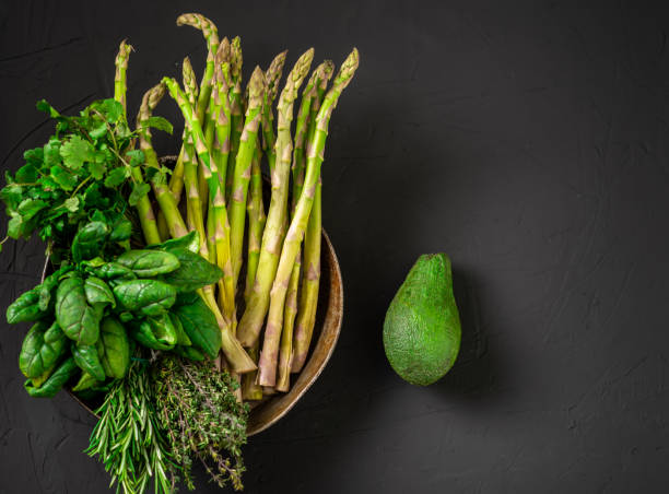 istock Avocado and various green vegetables on a dark background. Asparagus, spinach, rosemary. Vegetarian food concept. 1417741799