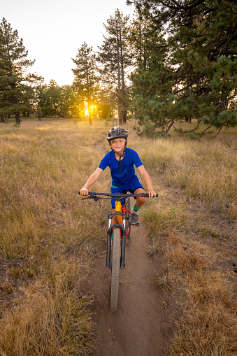 A Boy Riding His Mountain Bike across a wooden bridge in a meadow at sunset in Mt Laguna, Cleveland National Forest, California.  Big Laguna Trail.
