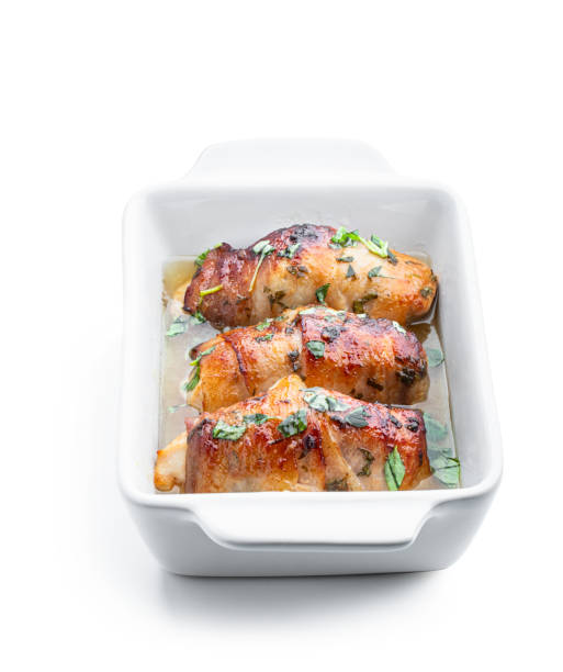 Chicken breasts wrapped in bacon in white dish isolated on white